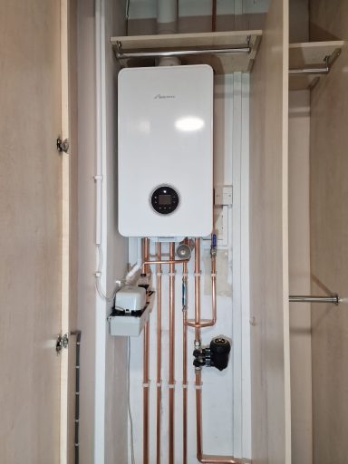 A wall-mounted boiler and exposed copper pipes in a utility space.