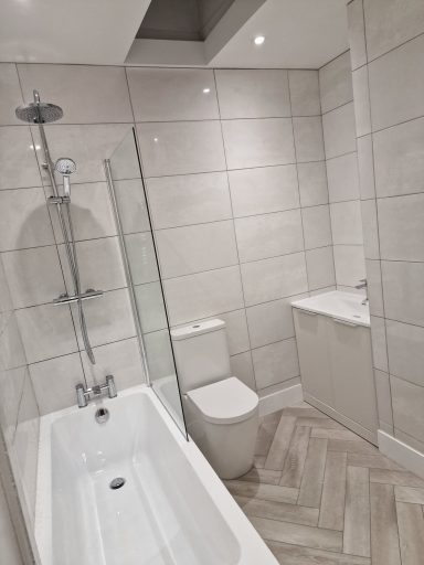 Modern bathroom featuring a bathtub, shower, toilet, and minimalist design.